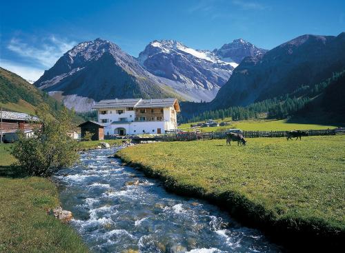 a river in a field with a house and cows grazing at Walserhuus Sertig in Sertig Döfli