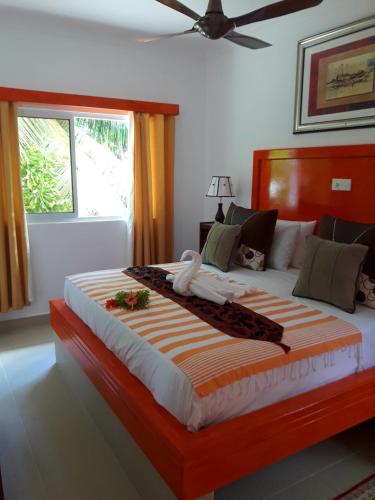 a bedroom with a large bed with an orange and white blanket at Villa Admiral in Anse Possession