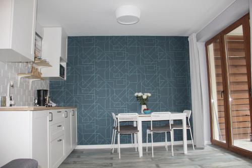 een keuken met een tafel en stoelen en een blauwe muur bij Apartament Justyna in Stegna