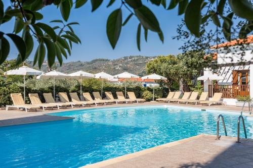 una piscina con tumbonas y sombrillas en Maistros Suites - Péra, en Skopelos Town