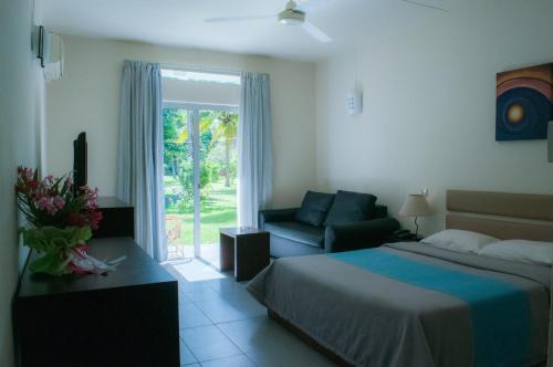 a bedroom with a bed and a couch and a window at Casa Florida Hotel & Spa in Pereybere