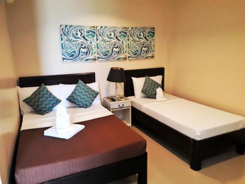 a bedroom with two beds and a table with a lamp at Bayview Country Inn El Nido in El Nido