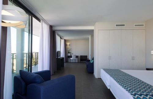 a bedroom with a bed and two blue chairs in a room at Altafulla Mar Hotel in Altafulla
