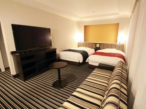 a hotel room with two beds and a flat screen tv at APA Hotel Fukuoka Watanabedori Ekimae EXCELLENT in Fukuoka