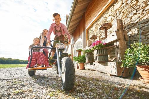 a woman and two children riding on a tricycle at Ferienhof Stetter in Schöllnach
