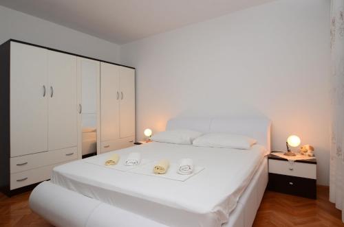 a white bedroom with a large white bed and cabinets at Apartments Marijana in Zavalatica