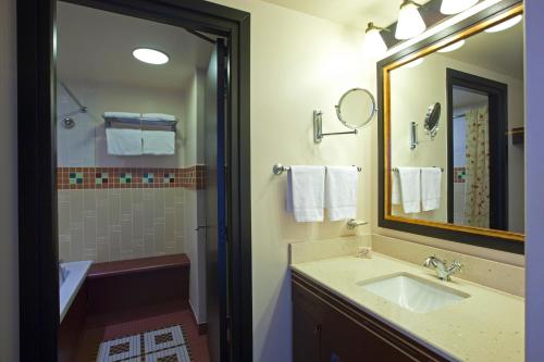 a bathroom with a sink and a mirror and a tub at Disney Sequoia Lodge in Coupvray