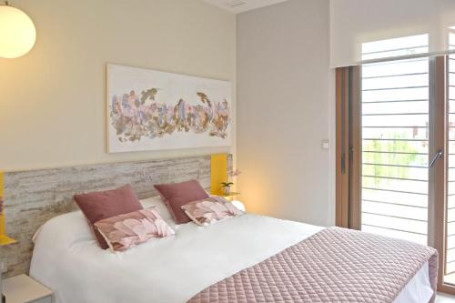 a bedroom with a large white bed with pink pillows at Terrazas de Campoamor by Mar Holidays in Playas de Orihuela