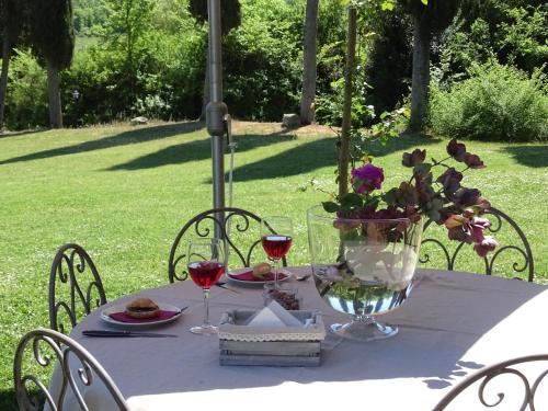 a table with a vase of flowers and wine glasses at Podere Pievina Delle Corti - Dimora di Campagna in Sinalunga