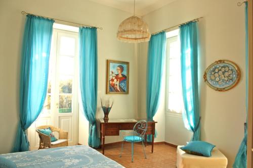 Ca' Del Sol في كالياري: غرفة نوم مع ستائر زرقاء ومكتب وسرير