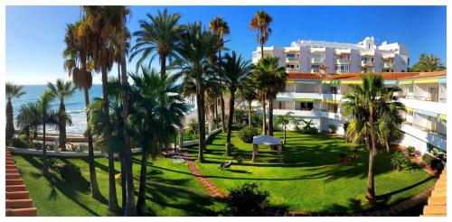 Blick auf ein Resort mit Palmen und das Meer in der Unterkunft Apartamentos Playa Torrecilla in Nerja