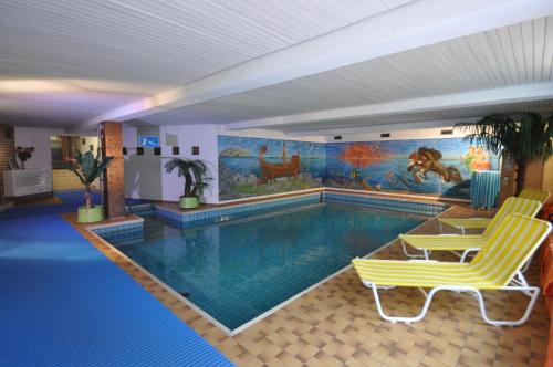 a swimming pool with two yellow chairs and a mural at Apart Hotel Stadtgarten in Überlingen