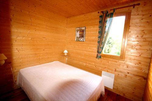 sypialnia z łóżkiem w drewnianym pokoju z oknem w obiekcie Les Chalets du Domaine des Soyeux w mieście Saint-Julien-Molin-Molette