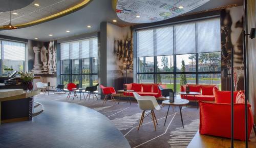 a waiting room with red chairs and tables and windows at Ibis Istanbul Tuzla Hotel in Tuzla