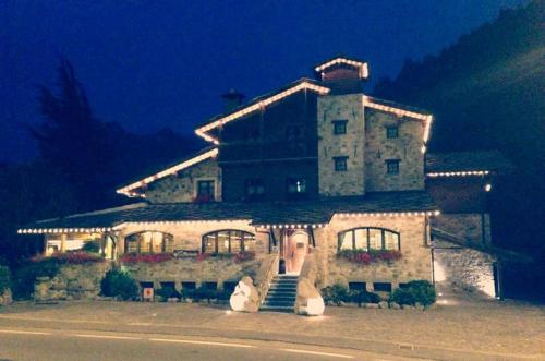a woman sitting in front of a building at night at Relais Del Nazionale in Vernante