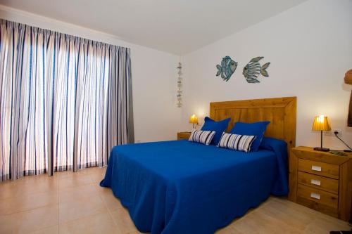 - une chambre dotée d'un lit bleu avec des draps et des rideaux bleus dans l'établissement Casa Paradise, à El Cotillo