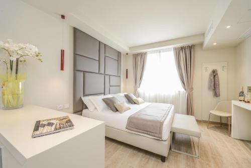 a white bedroom with a bed and a desk at Hotel Villa Garuti in Padenghe sul Garda