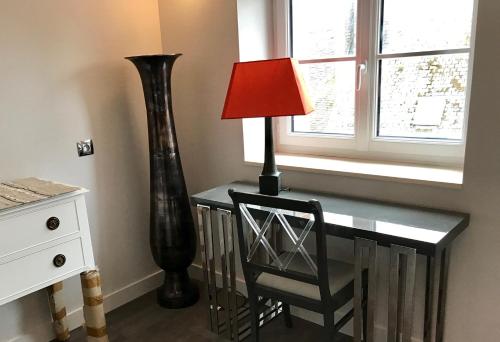 a desk with a lamp and a chair next to a window at LOGIS Hotel-Restaurant Le Relais d'Aligre in Châteauneuf-en-Thymerais