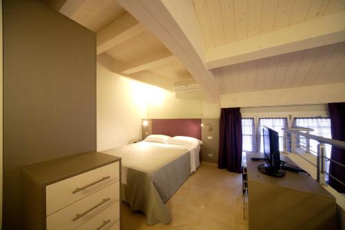 a bedroom with a bed and a desk with a television at Residence Hotel Le Viole in Rimini