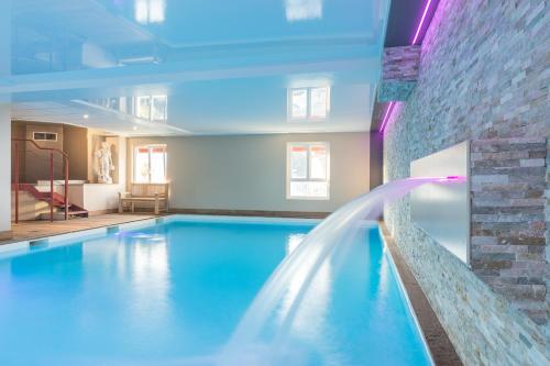 a large swimming pool with a water fountain at La Closerie SPA & Résidence Hôtel in Deauville