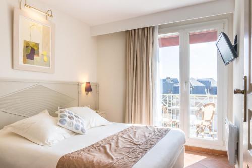 Cette chambre d'hôtel comprend un lit et un balcon. dans l'établissement Résidence La Closerie Deauville, à Deauville
