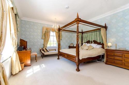 a bedroom with a canopy bed and a chair at Northolme Hall mansion with pool in Wainfleet All Saints