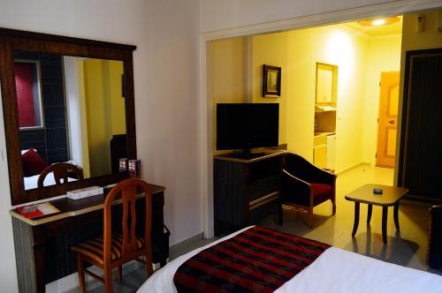 a bedroom with a bed and a desk with a television at Elysee Residence in Beirut