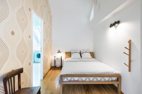 a white bedroom with a bed and a table at Odorico by Cocoonr in Rennes