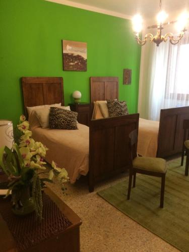 a green bedroom with two beds and a chair at Appartamento Turistico Dal Morino in Castiglione dei Pepoli