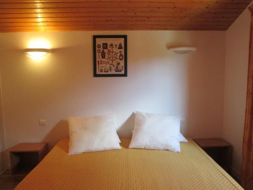 um quarto com uma cama com duas almofadas brancas em Résidence AMARINE em Capbreton