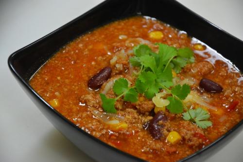 a black dish of soup with beans and a garnishment at Hotel Cesarski - Kaiserhof in Giżycko