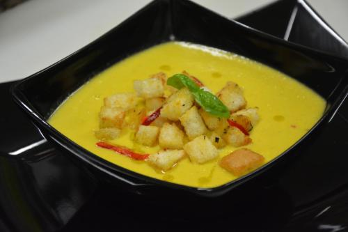 a black bowl of soup with tofu and peppers at Hotel Cesarski - Kaiserhof in Giżycko