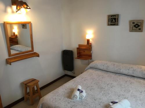 a small bedroom with a bed and a mirror at Entre Sierras in Villa General Belgrano