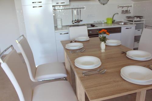 una cocina con una mesa de madera con placas blancas. en Maria's Paradise en Nin
