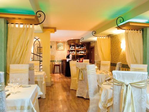 un restaurante con mesas y sillas blancas y una camarera en Capitol Hotel, en Varna