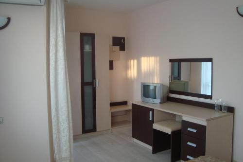 um quarto com uma secretária, uma televisão e um espelho em Hotel Astra em Ravda