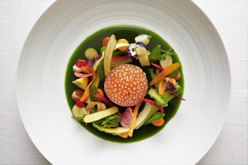 a salad in a green bowl on a white plate at Hotel des Berges, Restaurant Gastronomique & Spa in Illhaeusern