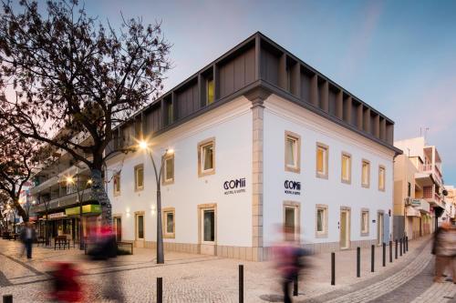 un edificio blanco con techo negro en una calle en Hostel Conii & Suites Algarve, en Quarteira