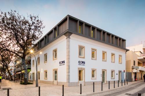 un edificio blanco con techo negro en una calle en Hostel Conii & Suites Algarve, en Quarteira