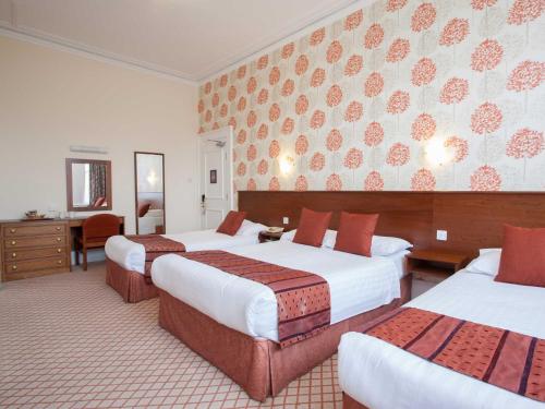 a hotel room with three beds and a desk at TLH Toorak Hotel - TLH Leisure, Entertainment and Spa Resort in Torquay