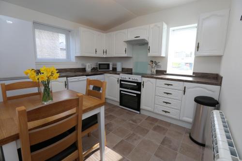una cocina con armarios blancos y una mesa con flores amarillas en Chapman's en Stornoway