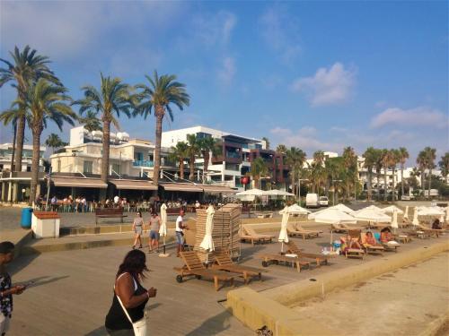 a beach with chaise lounges and chairs and palm trees at 777 Beach Guesthouse in Paphos City