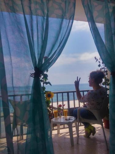 a woman sitting on a balcony looking out at the ocean at 777 Beach Guesthouse in Paphos City