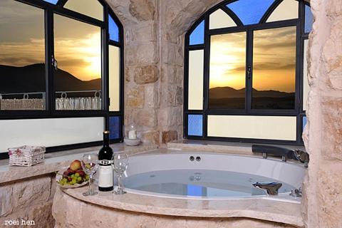 a bathroom with a large tub with two windows at Old City Inn in Safed