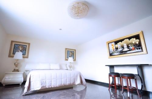 a white bedroom with a bed and two chairs at Paris Suites Hotel in Queens