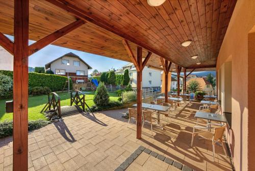a patio with a wooden pergola with tables and chairs at Penzion Krumlov - Massage studio in Český Krumlov