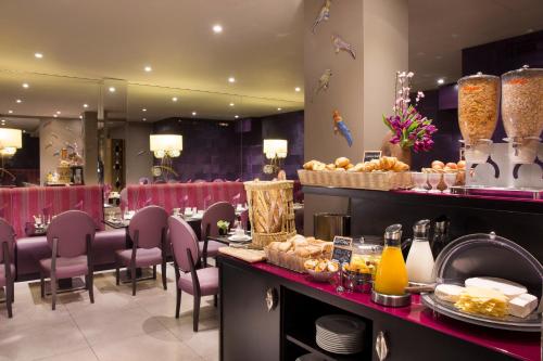 a restaurant with red chairs and a table with food at Hôtel Mondial in Paris