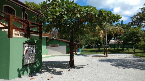a tree in front of a building with a sign at Morada dos Colibris in Boicucanga