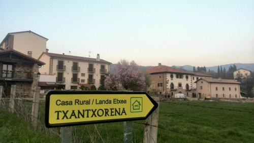 a sign in a field with buildings in the background at Txantxorena in Zubiri
