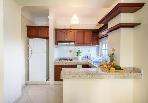 a kitchen with wooden cabinets and a white refrigerator at Hotel Shakey in Santo Domingo